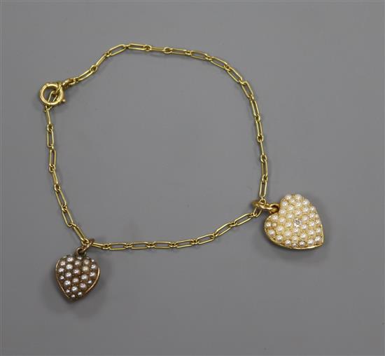 A French 18ct yellow metal bracelet, hung with two yellow metal and seed pearl set heart shaped charms, one with diamond.